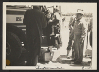 [recto] Arriving at the assembly center, the man at the right is a volunteer Japanese worker assisting at the induction. ;  Photographer: Lange, Dorothea ;  San Bruno, California.