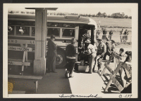 [recto] San Francisco family end first stage of evacuation and are seen leaving the bus at the Tanforan Assembly Center. ;  Photographer: Lange, Dorothea ;  San Bruno, California.