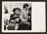 [recto] Turlock, Calif.--These young evacuees of Japanese ancestry are waiting their turn for baggage inspection upon arrival at this Assembly Center. ;  Photographer: Lange, Dorothea ;  Turlock, California.