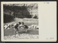[recto] Manzanar, Calif.--Evacuee children enjoying a hot summer afternoon in the mountain creek which flows through the desert on the border of this War Relocation Authority center. ;  Photographer: Lange, Dorothea ;  Manzanar, California.