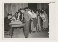 [recto] Attendants register arrivals at Santa Anita Park Assembly Center and assign them, family by family, to new quarters. The family unit is kept intact. These evacuees of Japanese ancestry are transferred later to War Relocation Authority Centers for the dura