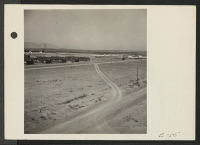 [recto] One corner of the Topaz Relocation Center. White buildings at the right are military police barracks and headquarters, and on the left is the evacuee hospital. ;  Photographer: Parker, Tom ;  Topaz, Utah.