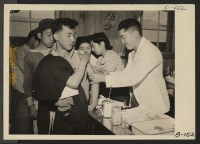 [recto] Manzanar, Calif.--Newcomers are vaccinated by evacuee nurses and doctors upon arrival at War Relocation Authority centers for evacuees of Japanese ancestry. ;  Photographer: Albers, Clem ;  Manzanar, California.
