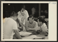 [recto] Closing of the Jerome Center, Denson, Arkansas. W. O. Melton, Assistant Project Director, assists a group of block managers busily selecting captains and train monitors. ;  Photographer: Iwasaki, Hikaru ;  Denson, Arkansas.