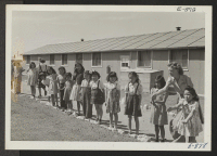 [recto] View showing Elementary children landscaping the grounds in front of their barracks school. ;  Photographer: McClelland, Joe ;  Amache, Colorado.