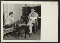 [recto] In a corner of the recreation room at the Greater New York Relocation Hostel Charles Taguchi (left) and Susumu Igauye, ...