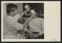 [recto] Dr. Nobuo Renge applies an eye bandage to George Arita in the center hospital clinic. All functions of the hospital are performed by center residents (former west coast persons of Japanese ancestry), except for the chief doctor and the superintending nurs