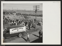 [recto] A view at the entrance to the Heart Mountain Relocation Center as residents and center officials wait for transferees on trip 24 from Tule Lake to unload. The ambulance is for the few hospital cases while others walked from the train to the induction cent