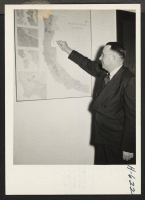[recto] R. B. Cozzens, Assistant Director, WRA, in a symbolic gesture, wipes the relocation centers from the map on the wall of his San Francisco office. ;  Photographer: Mace, Charles E. ;  San Francisco, California.