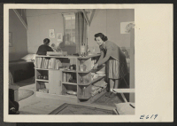 [recto] S. Nako, a young Nisei, evacuated from west coast defense areas, constructed, out of scrap and mail order lumber, shelving and furniture to increase the livability of his Heart Mountain barracks home. ;  Photographer: Parker, Tom ;  Heart Mountain, Wy