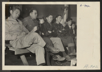 [recto] A group of residents of Japanese descent listening to the purpose of the registration which was held at this center. The registration forms were explained to the evacuees by WRA and Army officials. ;  Photographer: Stewart, Francis ;  Manzanar, Califo
