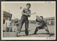 [recto] Sixth grade boys enjoy a game of ball at recess time. Note boys in rear who mistrust control of the speed ball pitcher. ;  Photographer: Stewart, Francis ;  Manzanar, California.