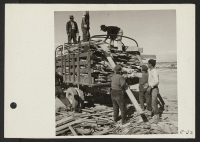 [recto] A group of volunteer workers at the Topaz Relocation Center gathering a truck load of scrap lumber from the contractor's scrap pile. ;  Photographer: Parker, Tom ;  Topaz, Utah.