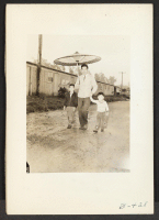 [recto] Arcadia, Calif.--Japanese parasol for spring showers at Santa Anita Park assembly center. Evacuees later are transferred to War Relocation centers for the duration. ;  Photographer: Albers, Clem ;  Arcadia, California.