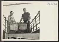 [recto] Shoichiro Inada, Issei resettler employed by the Vegetable Packing House, Chicago, helps Fred Sietmann, vegetable grower from Des Plaines, Illinois, ...