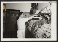 [recto] James Yoshida, who is weighing vegetables for a customer, is in charge of the produce department of the Media Cooperative store in Media, Pennsylvania. He came from the Heart Mountain Relocation Center. ;  Media, Pennsylvania.