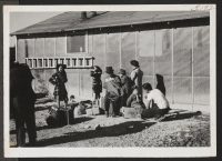 [recto] Family group in Topaz waiting for bus to convey them to the Tule Lake bound train. ;  Topaz, Utah.