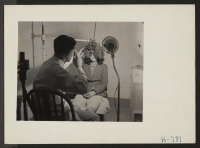 [recto] Hospital Series. Dr. examining eyes of girl. George Tani, optometrist. Former occupation: optometrist. Former residence: Oakland, California. ;  Photographer: Stewart, Francis ;  Hunt, Idaho.