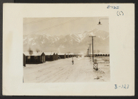 [recto] Manzanar, Calif.--Street scene and view of quarters for evacuees of Japanese ancestry at Manzanar reception center. High Sierras in background. ;  Photographer: Albers, Clem ;  Manzanar, California.