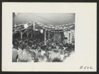[recto] Two Nisei girls perform a Hawaiian Hula at a block talent show held in the mess hall. Acts include everything from the older Eiseis performing folk lore chants and dances to Nisei renditions of boogie woogie blues on the clarinet or mouth organ. ;  Phot