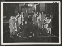 [recto] Miss Pearl Wright, principal, and one of her teachers playing a game with a few of the pupils, among whom ...