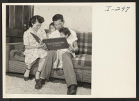 [recto] Chick Masaru Uno shows Sheila (age 6) and Naomi (age 2-1/2) a picture of their uncle, Master Sgt. Paul Uno ...