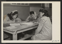 [recto] Mary Oki, a member of the Center Education Department, assisting in registering two young Nisei residents, Edith Yoshimoto (left), and ...