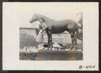 [recto] Arcadia, Calif.--Mrs. Lily Okura poses with statue of Seabiscuit in Santa Anita Park, now an assembly center for evacuees of Japanese ancestry. ;  Photographer: Albers, Clem ;  Arcadia, California.