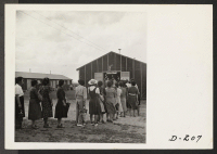 [recto] Admiring lines of evacuees filed through a recreation hall, which exhibited floral arrangements made by local craftsmen. ;  Photographer: Stewart, Francis ;  Newell, California.