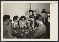 [recto] A mah jong game engages the attention of this group at a social at the Philadelphia, Pennsylvania, Hostel. Seated about ...