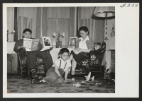 [recto] Mrs. Asa Tabata at home with William, 7, playing with toys on the floor, and George reading a book. The ...