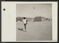 [recto] A warm sunny afternoon at the Topaz Relocation Center finds footballs in the air everywhere as young Americans of Japanese ancestry practice their favorite outdoor game. ;  Photographer: Parker, Tom ;  Topaz, Utah.