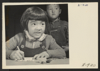 [recto] A third grade student at the Manzanar Relocation Center for evacuees of Japanese ancestry practices free hand drawing. This photo ...