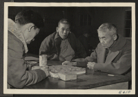 [recto] Shogi, a game very similar to Chess, is played in a recreation hall by persons of Japanese ancestry, evacuated from west coast areas. ;  Photographer: Parker, Tom ;  Heart Mountain, Wyoming.