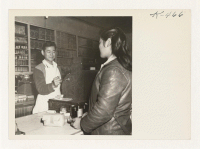 [recto] Shig Nishimoto rings up a sale in his newly opened general merchandise store. Shig had worked for one year in Benton Harbor, Michigan, after spending two years at Minidoka Relocation Center. He also owns several orchards around Penryn. ;  Photographer: