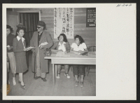 [recto] Induction Center. An elderly arrival from the Topaz Center is philosophical as he goes through the tedious routine of being inducted into the Tule Lake Center. One of the volunteer helpers is seen assisting him with his registration papers. ;  Photograp