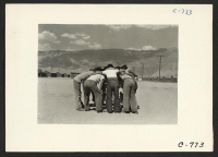 [recto] Manzanar, Calif.--Baseball players in a huddle. This game is very popular with 80 teams having been formed throughout the Center. Most of the playing is in the wide fire-break between blocks of barracks. ;  Photographer: Lange, Dorothea ;  Manzanar, C