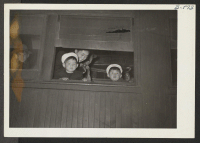 [recto] A couple of youngsters looking out the train window. ;  Photographer: McClelland, Joe ;  Amache, Colorado.