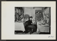 [recto] Mrs. Tom Kusumi in charge of the needlework exhibited at the Arts and Crafts Festival, which was sponsored in the center by the Education Division and the Pioneer, center newspaper. Note the crocheted dolls in the background. ;  Photographer: Coffey, Pa