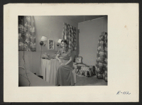 [recto] With a few yards of cloth and a nick nack or two, Miss Adeline Story, Caucasian teacher, has made her small dormitory room a comfortable spot. ;  Photographer: Parker, Tom ;  Heart Mountain, Wyoming.
