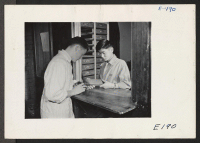 [recto] Mason Mamoda, relocated student of Japanese ancestry, assigns a tool from the stock room to Harold Largen, a fellow student in a wood working class at the University of Nebraska. (L to R) Harold Largen and Mason Mamoda, former residence, Minidoka Relocati