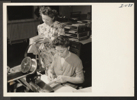 [recto] Mrs. Take Fujita is shown here operating a stitching machine together with her fellow worker Miss Mary Svite at the ...