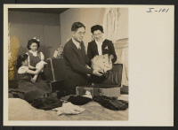 [recto] Mr. and Mrs. Thomas T. Sashihara and their daughters, Maureen and Diane, are shown packing their clothing prior to leaving ...