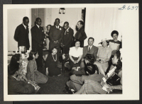[recto] During a social at the Philadelphia, Pennsylvania, Hostel, this group of resettlers and Caucasian friends listens to spirituals sung by ...