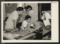[recto] Ray Komai (seated), layout artist for a leading New York advertising agency, is shown with two of his fellow workers, ...
