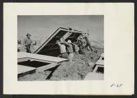 [recto] Pre-fabricated wall sections are raised at the place by contractor's workers in constructing barracks at this relocation center. Former residence: Merced Assembly Center, Merced, California. ;  Photographer: Parker, Tom ;  Amache, Colorado.