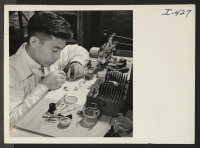 [recto] Noburu Zaiman is shown at his work showing a few precision instruments which he has to use. The work which ...