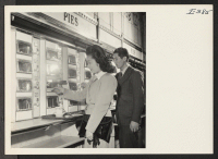 [recto] While lunching in one of New York City's famous Automat restaurants just off Fifth Avenue, May Tomio, Granada, and Akira Kashiki, Colorado River, are obtaining pieces of pie from the food receptacles. ;  Photographer: Iwasaki, Hikaru ;  New York, New