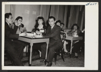 [recto] Social given by Omaha Y.M.C.A. for the evacuees. Refreshment time. Seated from left to right are Howard Hoshida, Ruth Foland, Betty Schuster, Setsuo Dairiki, Auzella Yamamoto, Paul Tosaya, and Marie Yamamoto. ;  Photographer: Okano, Tom K. ;  Kansas C