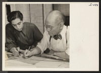 [recto] Mr. Soichi Yamamoto, formerly of Pasadena, California, and Gila River, is shown here with a fellow employee doing mechanical design ...